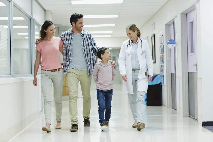 Full length of female doctor walking with family in hospital corridor