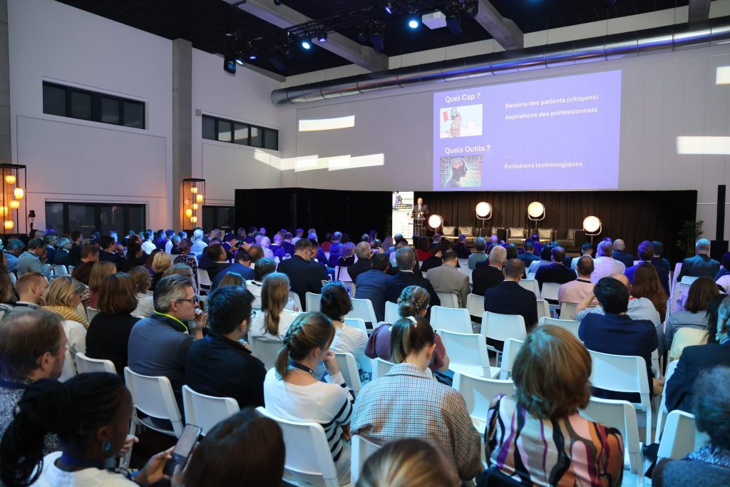 La salle plénière comble du Symposium WeLink.Care 2024 à Namur, vue depuis le fond